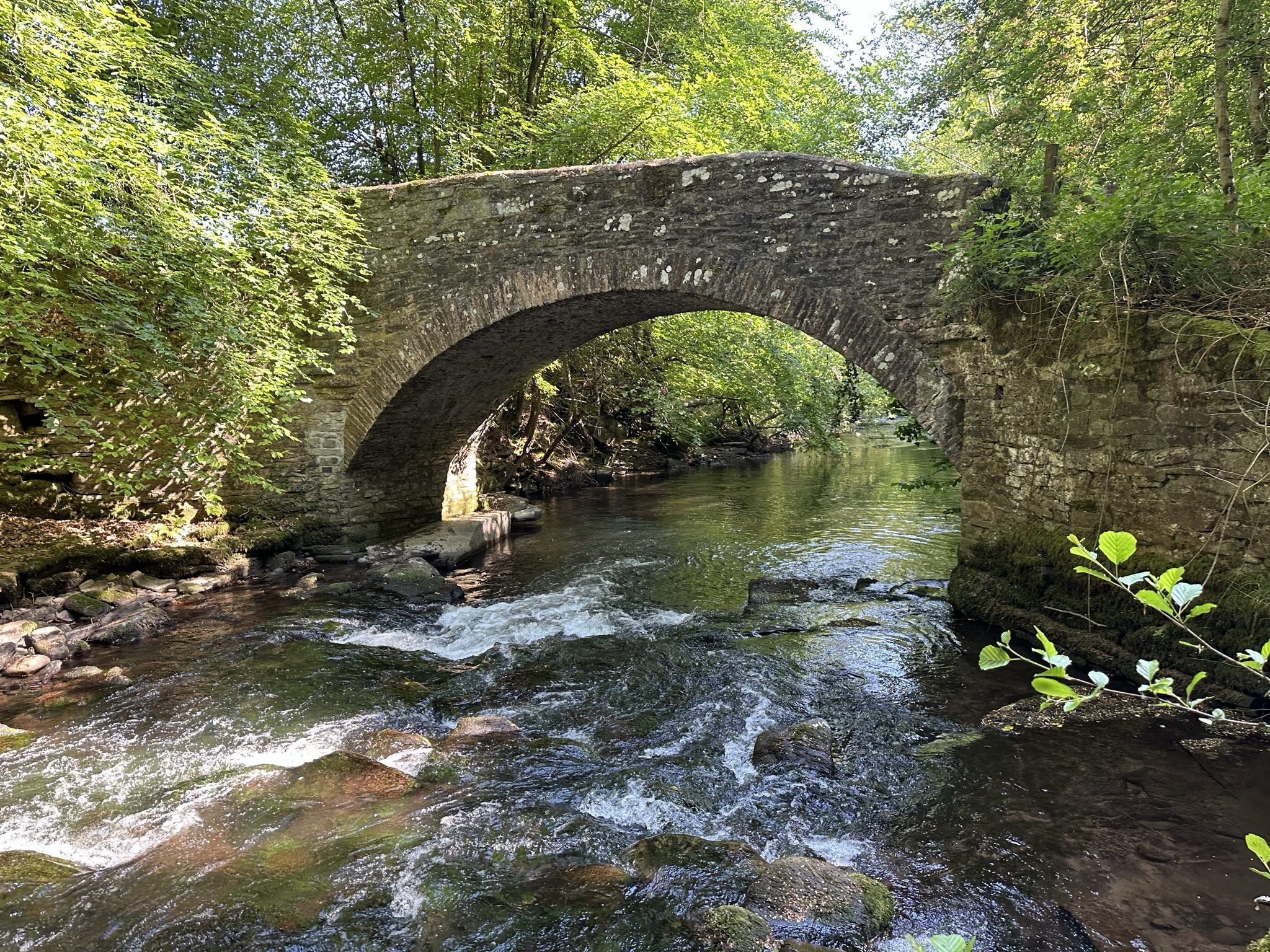 Butler&rsquo;s Bridge, an old stone arch over the river, with a natural swimming pool beneath and woodland all around