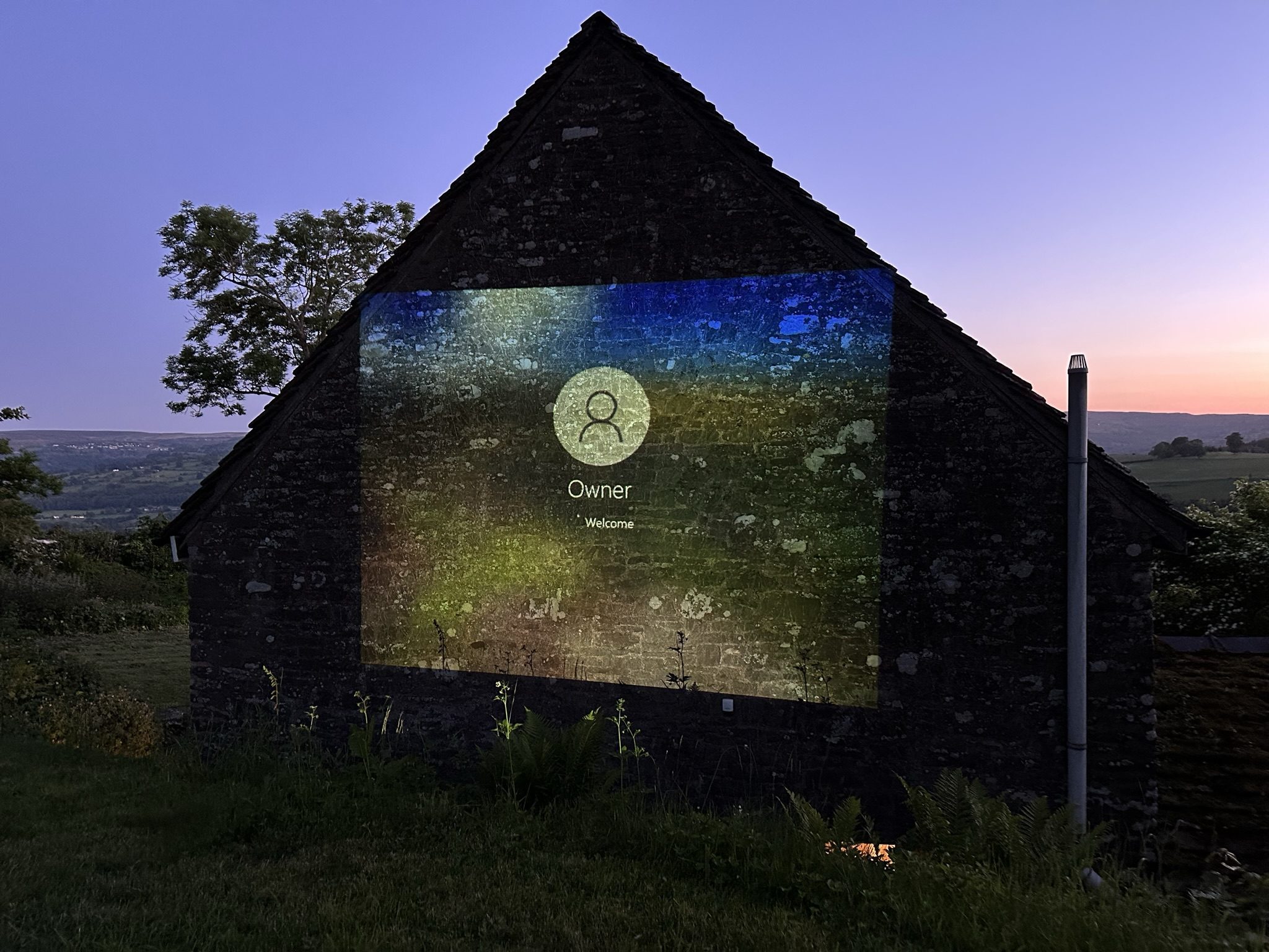 A film projected onto the stone gable end of the cottages on a summer evening, the valley beyond turning pink at dusk