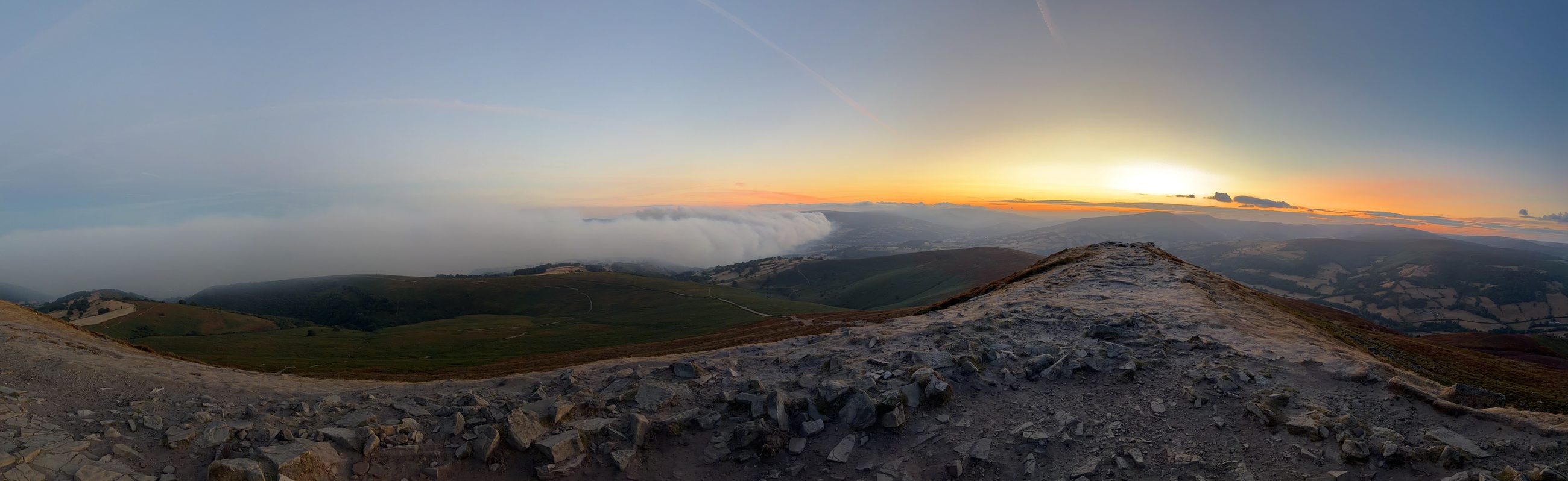 Panorama from a summit at sunset, a great wall of pale wildfire smoke pouring over the ridge and down into the valley below, 9 August 2026
