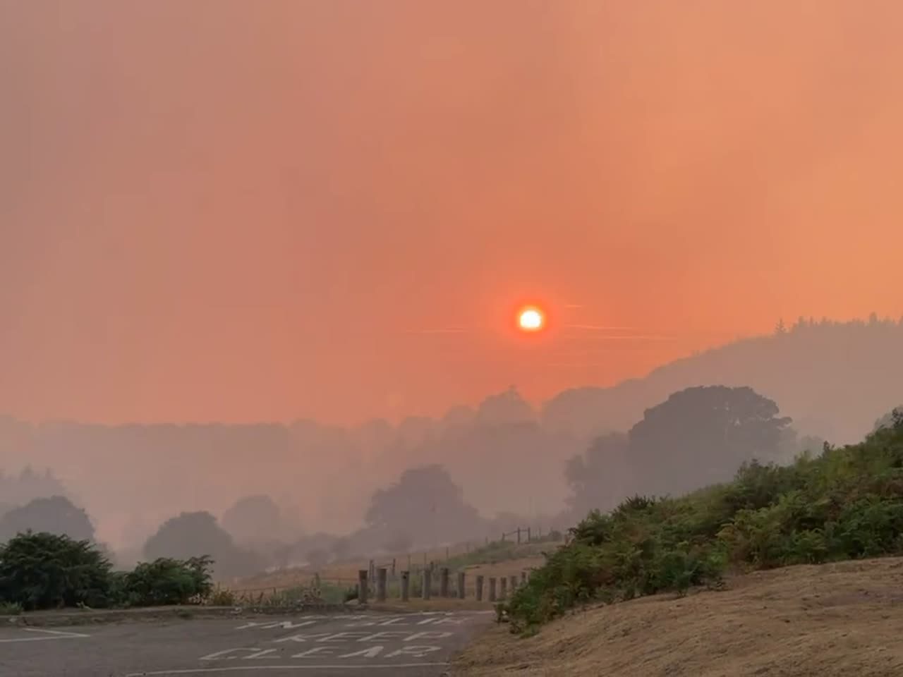 A blood-orange sun hanging in a sky thick with wildfire smoke, the valley hazed over